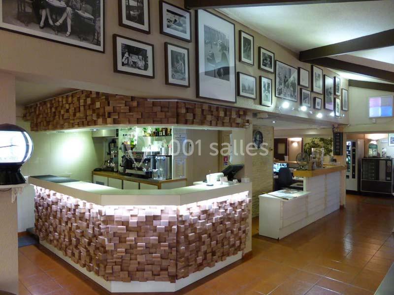 Comptoir de bar moderne en bois avec décorations murales de photos en noir et blanc dans un intérieur lumineux.