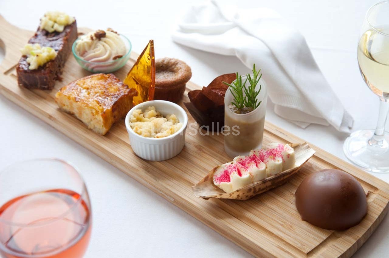 Plateau en bois avec divers desserts raffinés, incluant gâteaux, mousses, crumble et décorations gourmandes.
