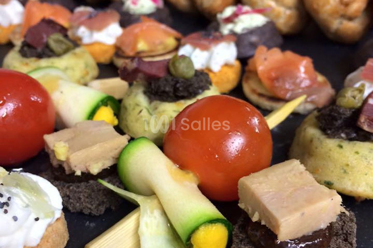 Assortiment de canapés variés avec légumes, foie gras, saumon fumé et garnitures colorées disposés sur un plateau.