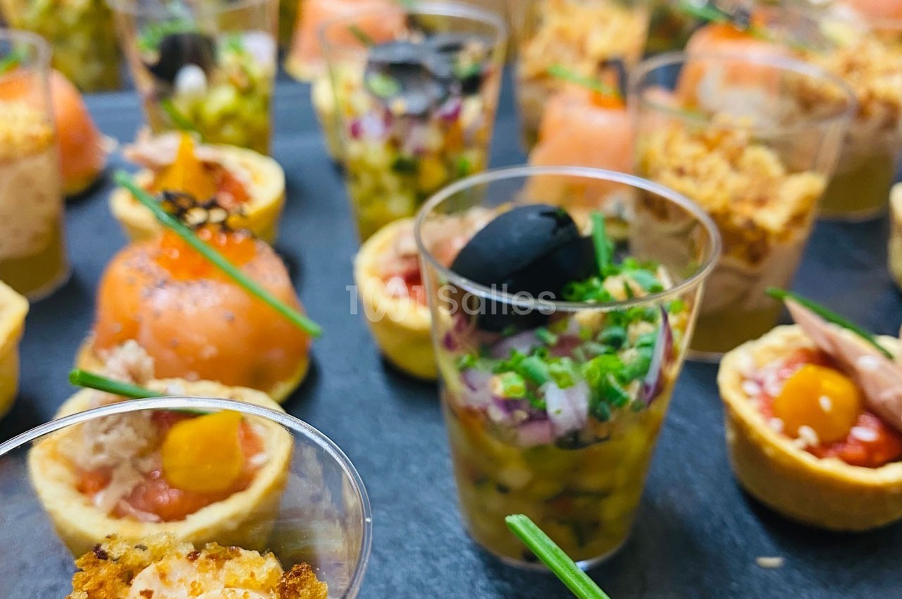 Assortiment de bouchées apéritives variées, comprenant verrines, tartelettes et préparations au saumon.