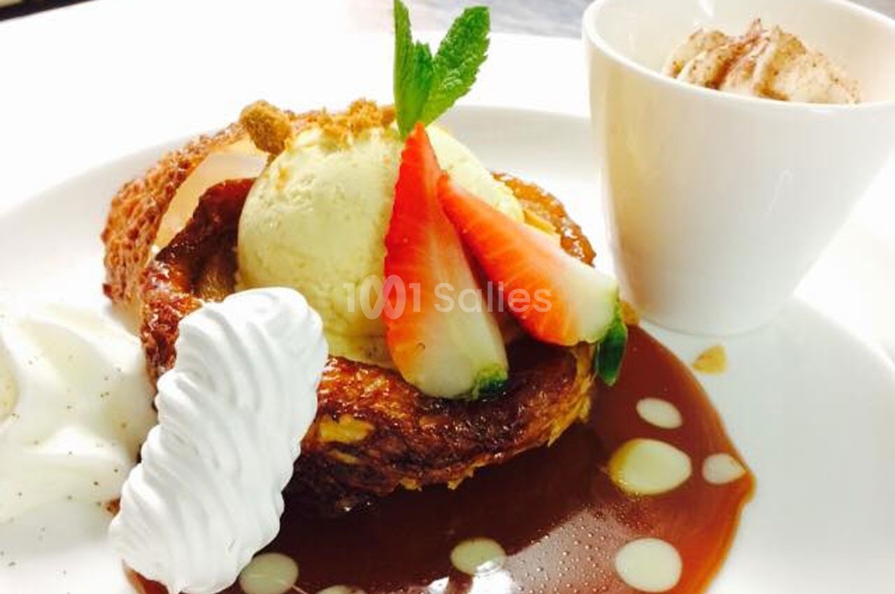 Dessert composé de brioche caramélisée, glace vanille, fraises, chantilly et sauce caramel, accompagné d'une mousse en…
