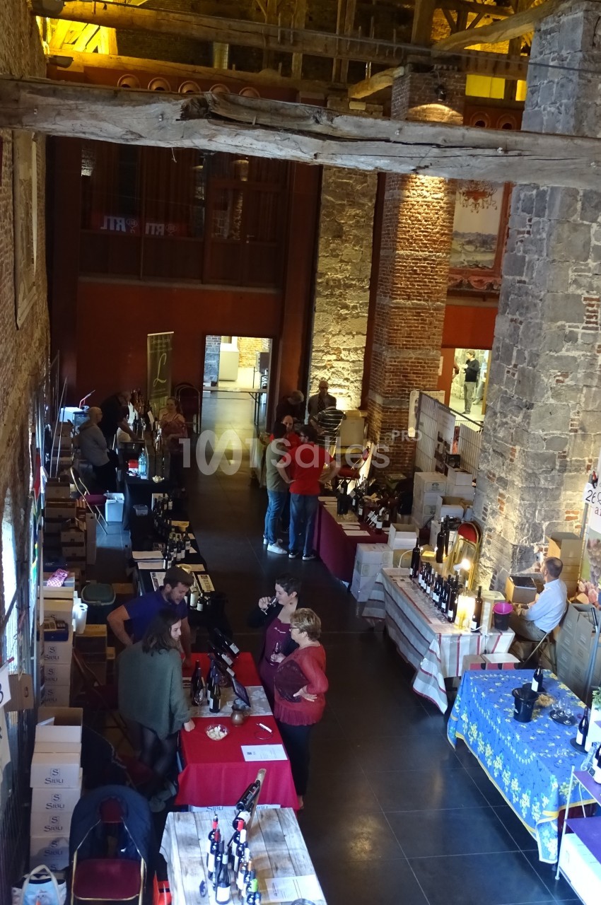 Vue d'un marché couvert avec des stands de produits locaux, des visiteurs et une architecture en pierre et bois.