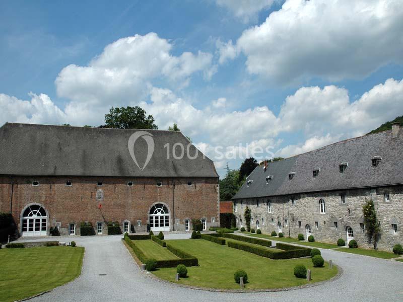 Bâtiments en pierre et briques avec toits en ardoise entourant une cour aménagée de pelouses et d'allées gravillonnées.