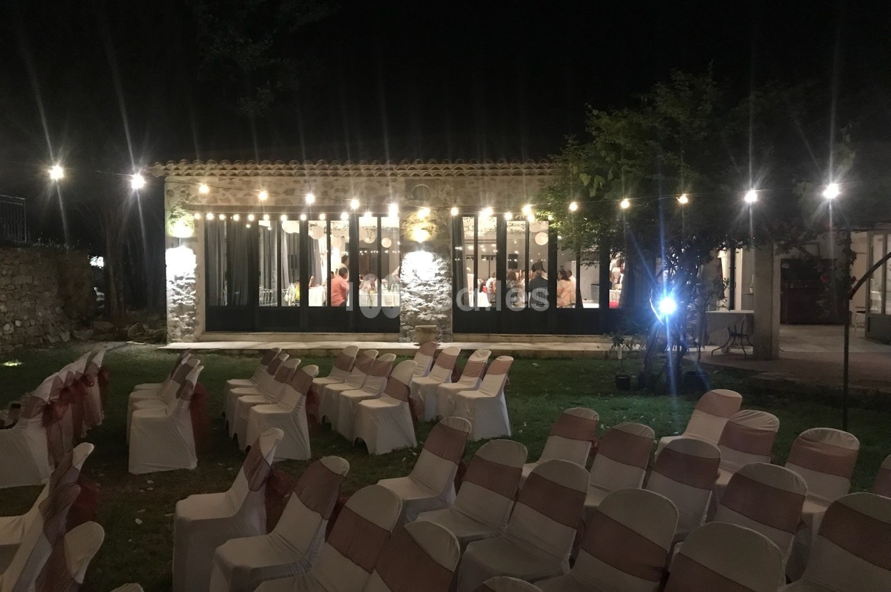 Salle éclairée en soirée avec des chaises disposées à l'extérieur, probablement pour un événement.