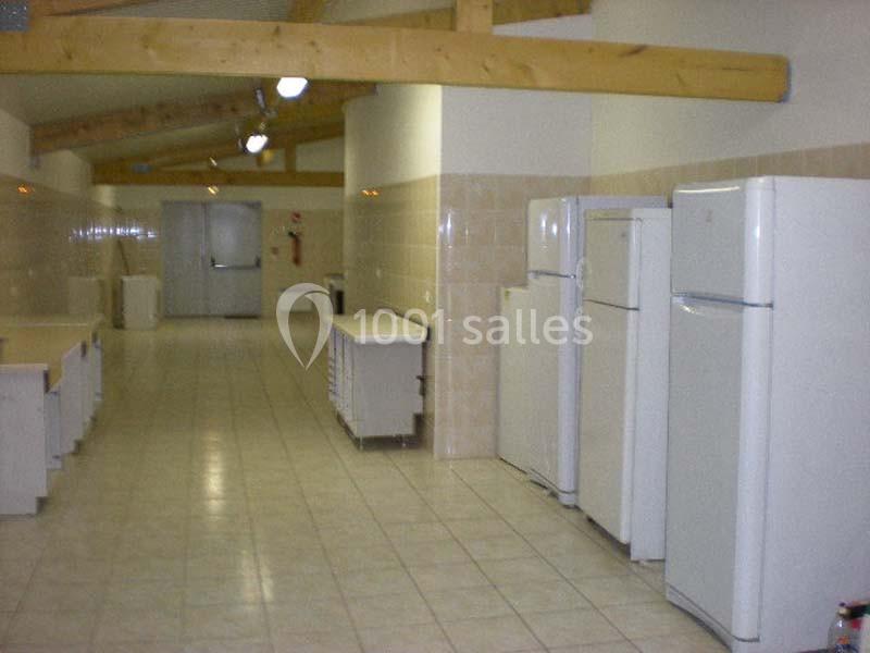 Cuisine collective avec plusieurs réfrigérateurs blancs alignés, plans de travail et plafond avec poutres apparentes.