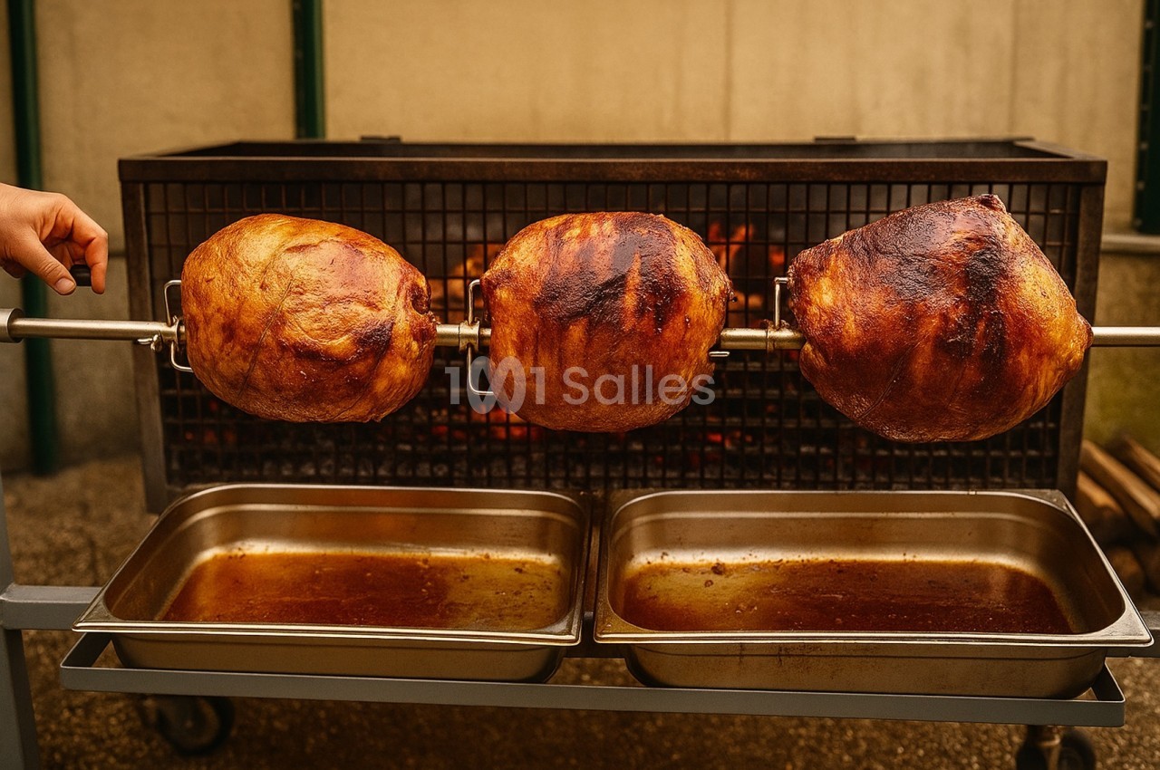 Trois morceaux de viande rôtissant sur une broche devant un feu, avec des bacs en dessous pour recueillir les jus.