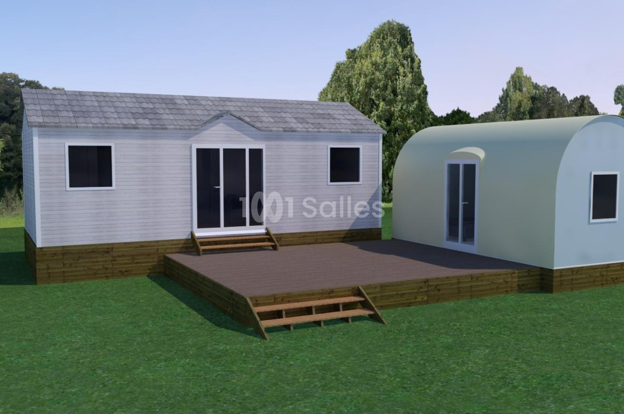 Deux modules préfabriqués en bois avec terrasse, situés sur une pelouse entourée d'arbres.