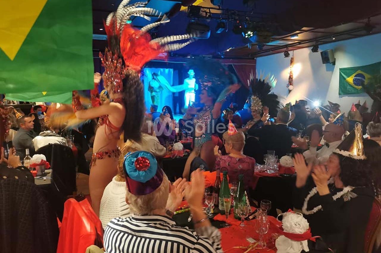 Danseuse en costume coloré se produisant sur scène lors d'une fête avec des spectateurs applaudissant, décorée de drapeaux…