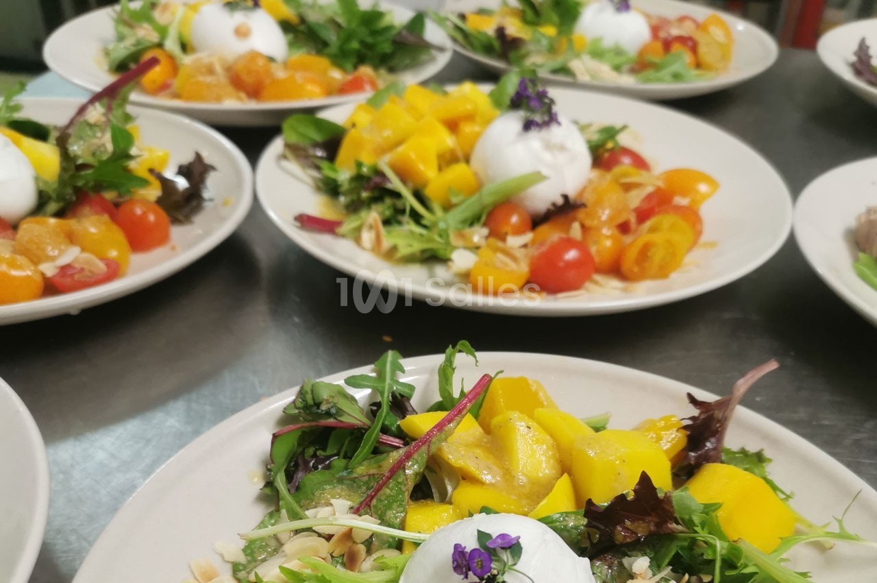 Assiettes de salades colorées garnies de burrata, tomates cerises, mangue et feuilles de salade, décorées de fleurs…
