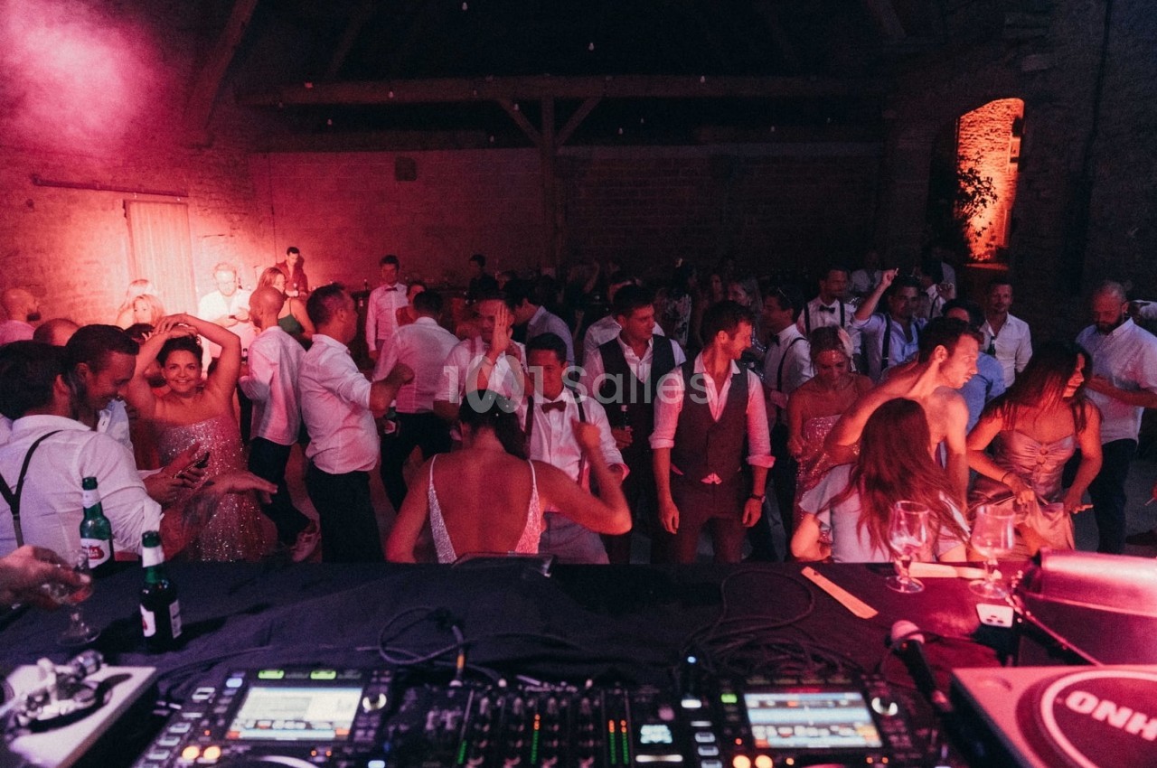 Des invités dansent et discutent lors d'une soirée festive dans une salle éclairée par des lumières tamisées.