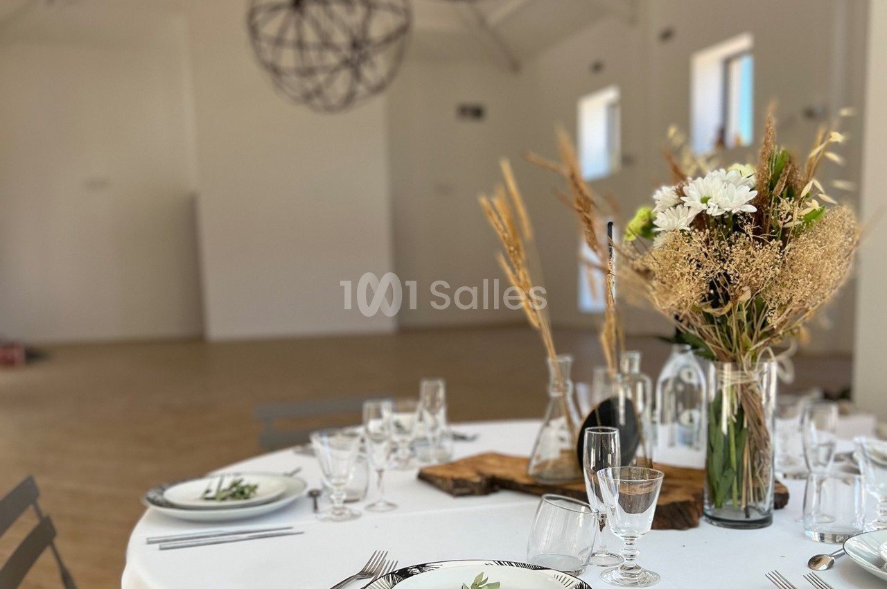 Table dressée avec vaisselle élégante, bouquet de fleurs séchées et décor minimaliste dans une salle lumineuse.