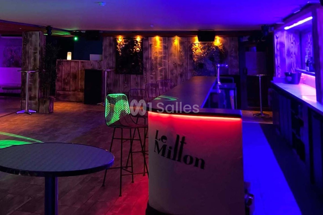 Salle de bar avec éclairage coloré, comptoir lumineux et chaises hautes dans une ambiance tamisée.