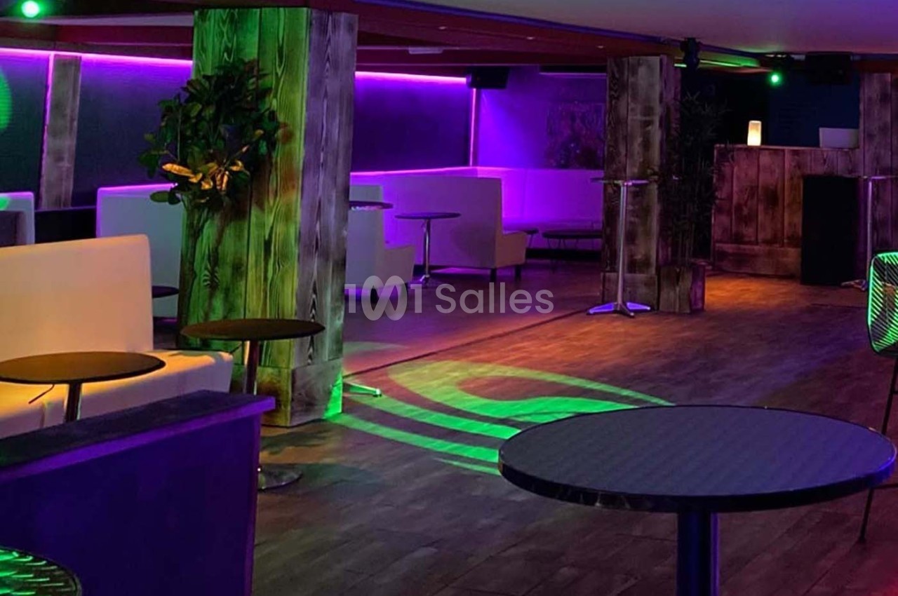 Salle de réception avec éclairage coloré, mobilier moderne et ambiance tamisée.