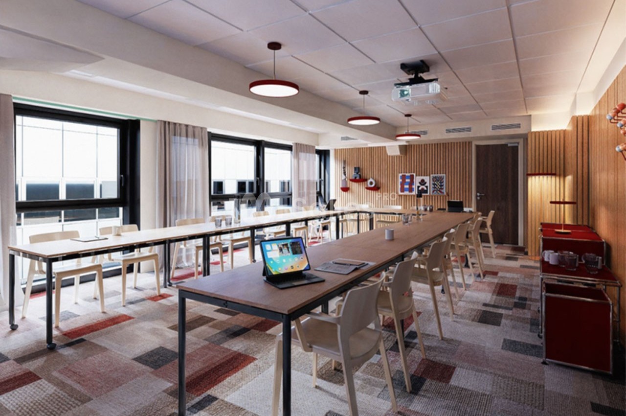 Salle de réunion lumineuse avec grandes fenêtres, tables en bois, chaises blanches et équipement de présentation.