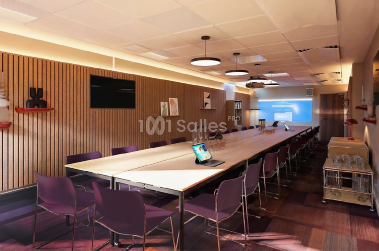 Salle de réunion moderne avec une longue table, des chaises violettes, un écran de projection et une décoration épurée.