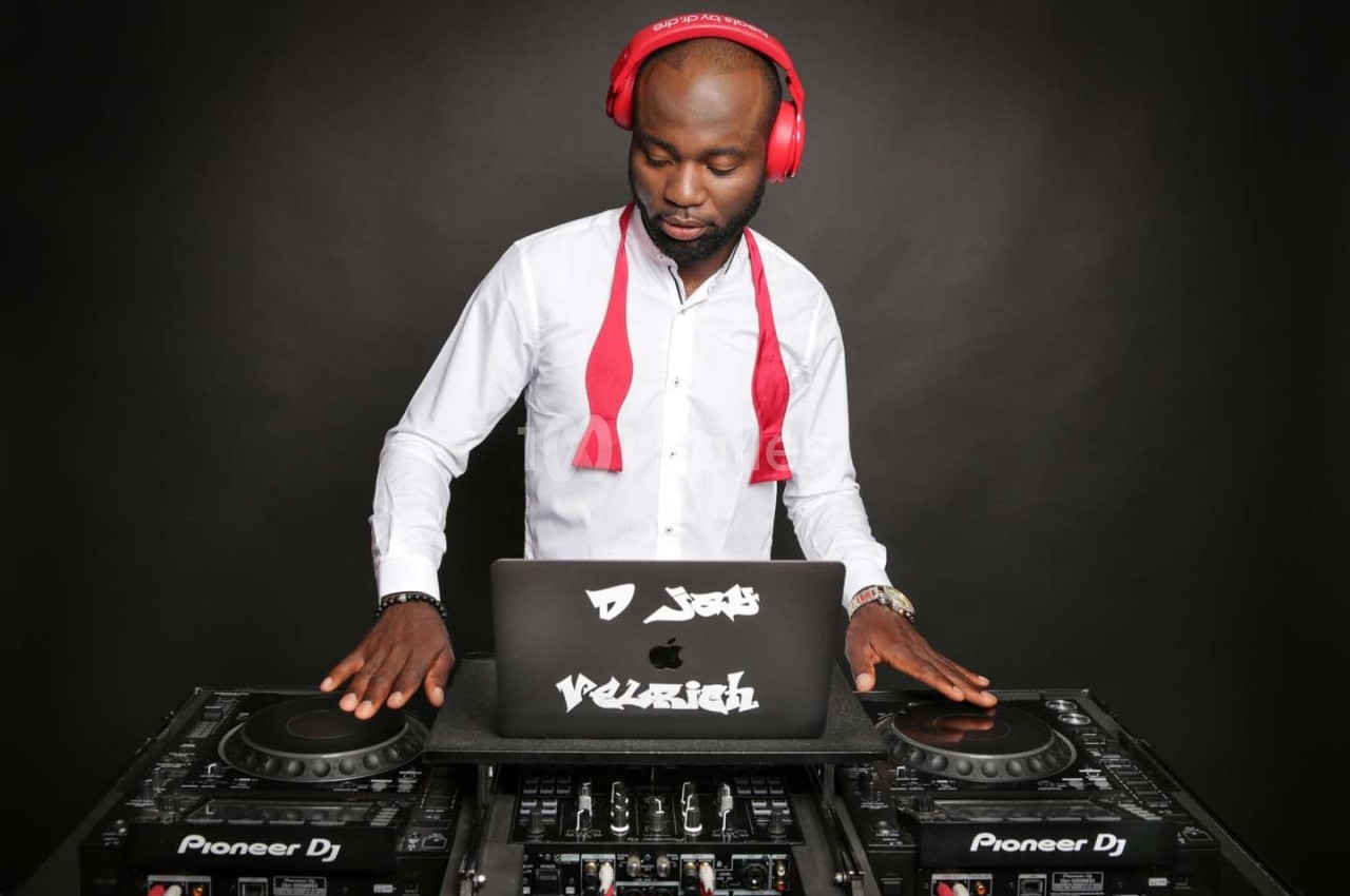 Un DJ portant un casque rouge mixe de la musique sur une table de mixage avec un ordinateur portable.