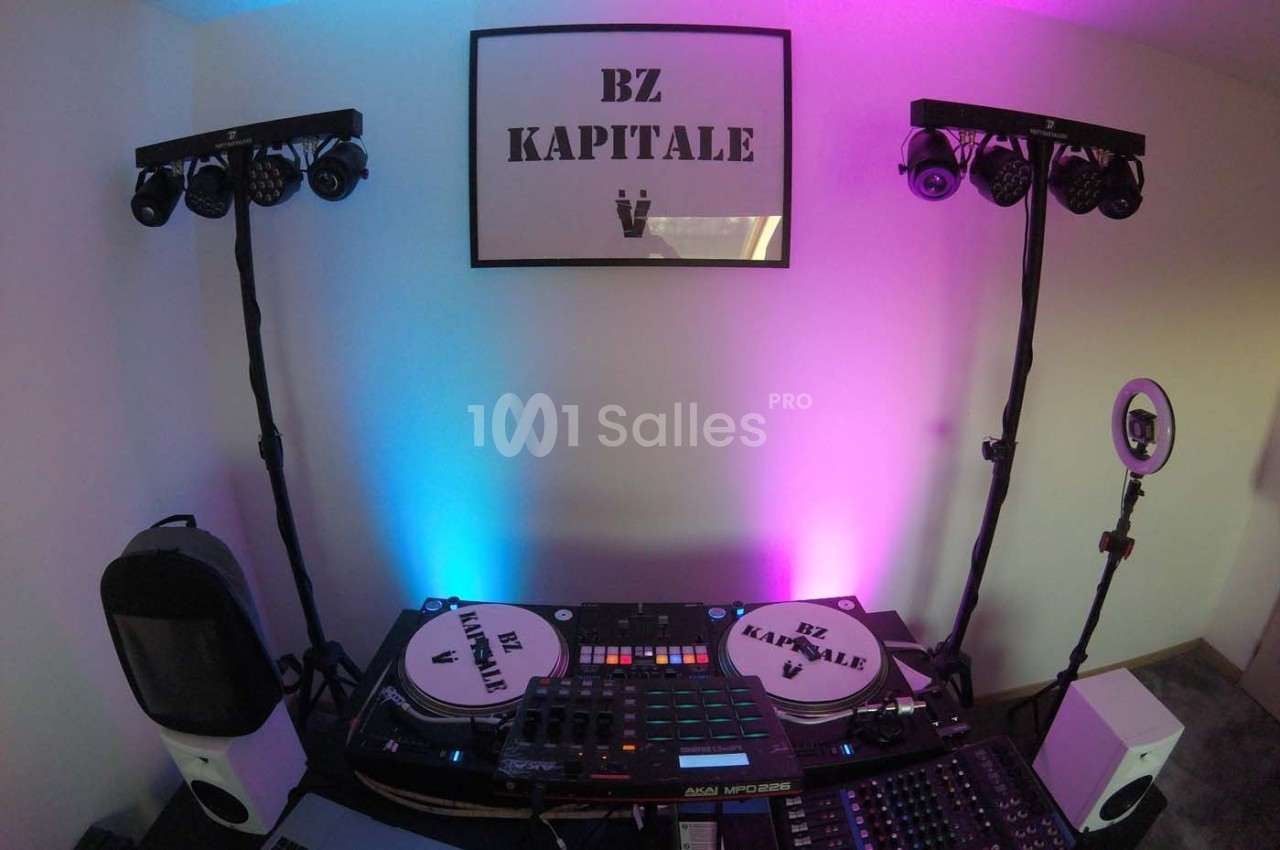 Équipement de DJ avec platines, table de mixage et éclairages colorés dans une pièce décorée.