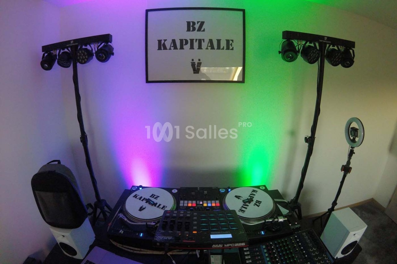 Équipement de DJ avec platines, table de mixage et éclairages colorés dans une pièce décorée sobrement.