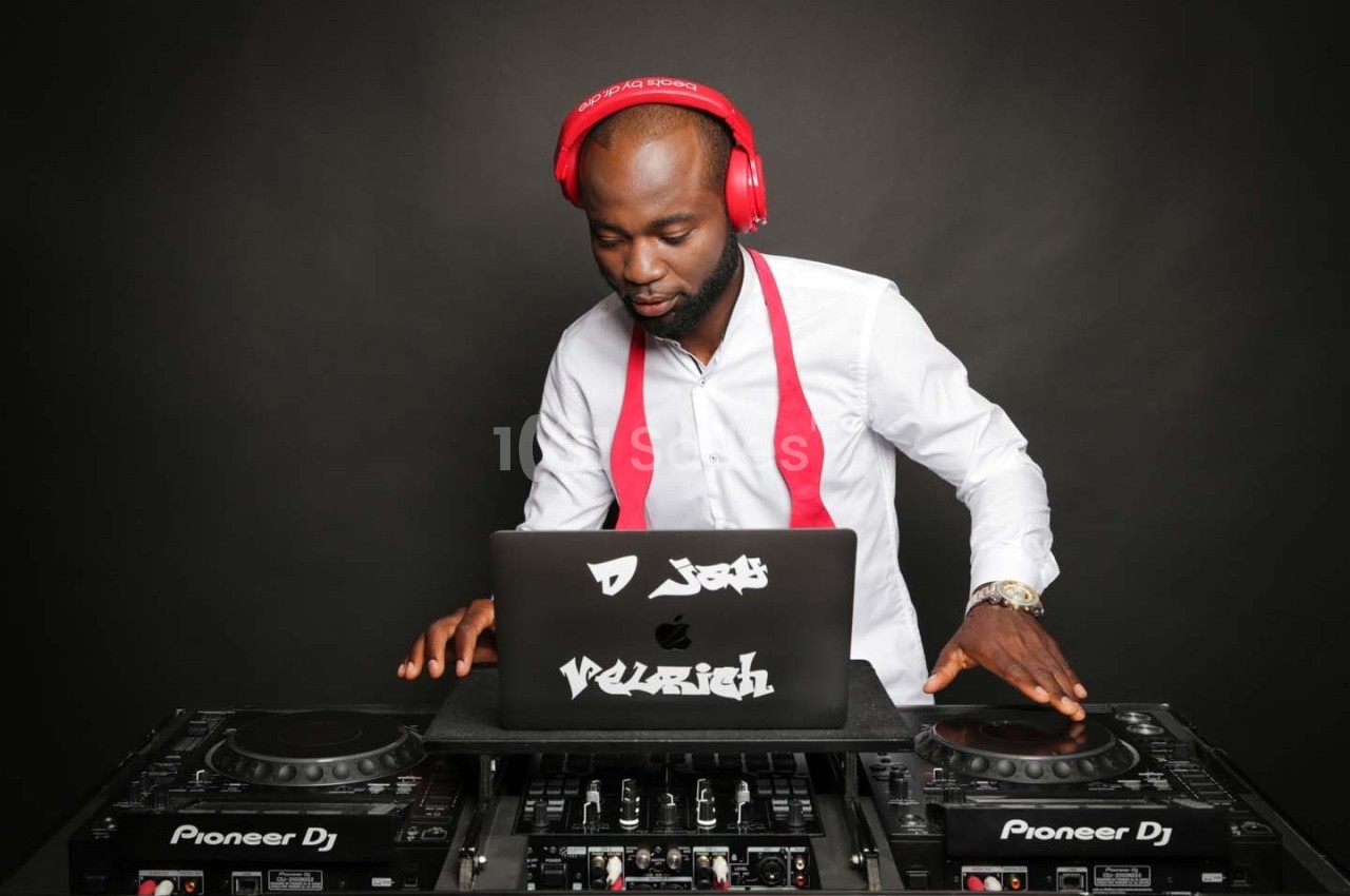 Un DJ portant un casque rouge mixe de la musique sur une table de mixage avec un ordinateur portable.