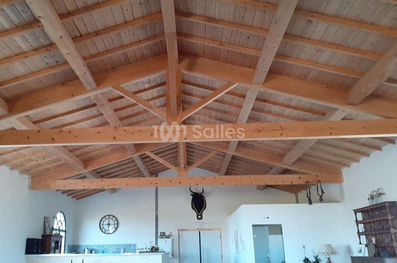 Plafond en bois avec poutres apparentes dans une pièce lumineuse, décorée d'objets muraux et d'une tête de taureau.