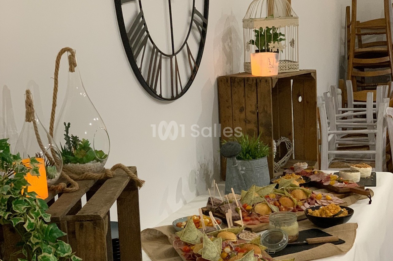 Table garnie de plats variés et décorations rustiques, avec une grande horloge murale en arrière-plan.