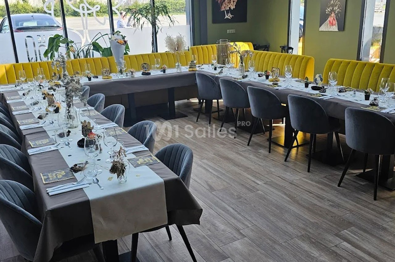 Salle de restaurant lumineuse avec tables dressées pour un événement, chaises grises et banquettes jaunes.