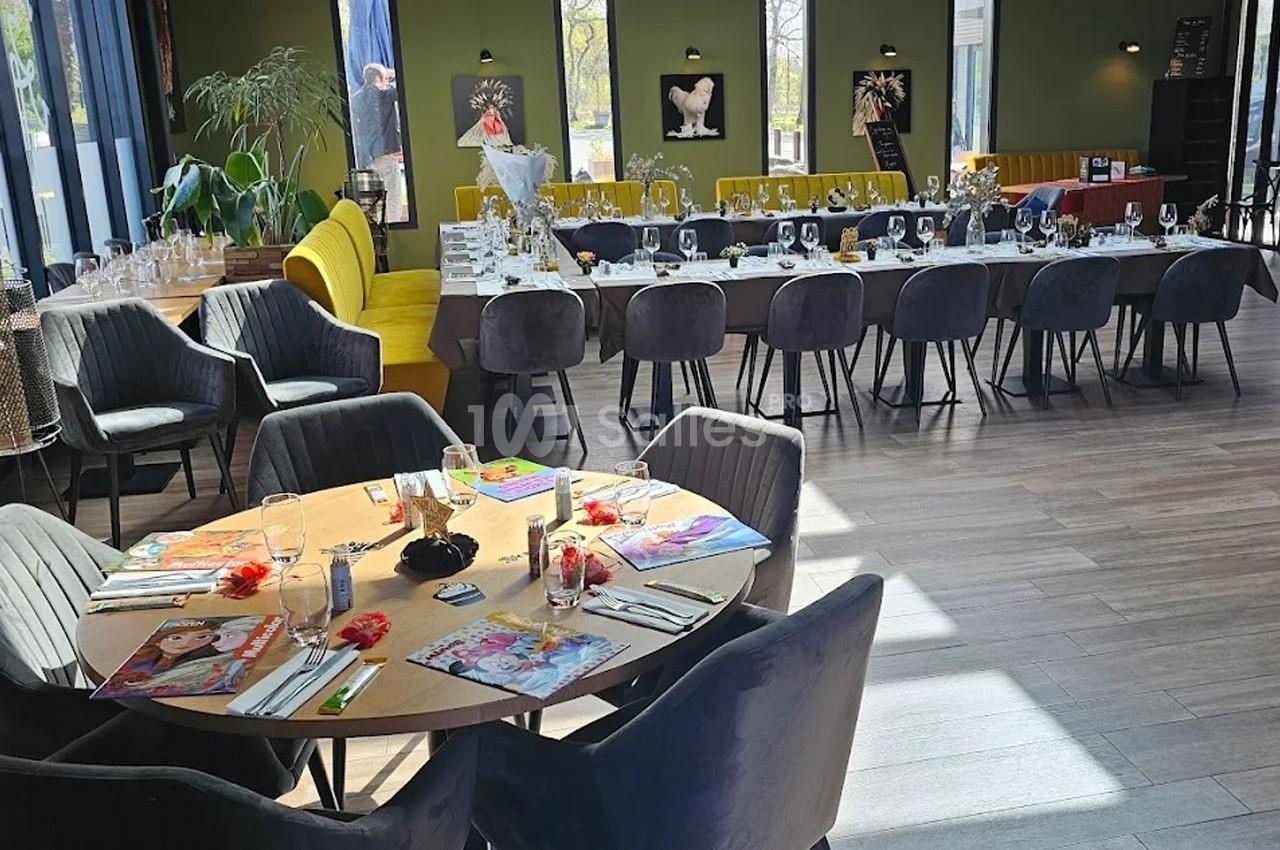 Salle de réception lumineuse avec tables décorées, chaises modernes et grandes baies vitrées donnant sur un espace extérieur.
