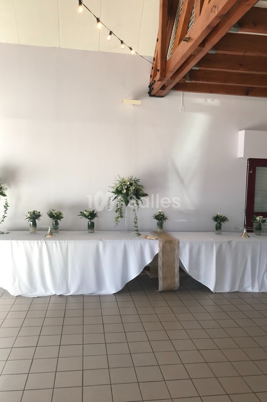 Table décorée avec une nappe blanche, ornée de bouquets de fleurs vertes et blanches, dans une salle lumineuse.