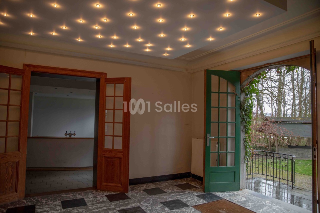 Intérieur avec sol en marbre, portes vitrées ouvertes et vue sur un jardin par une porte verte.