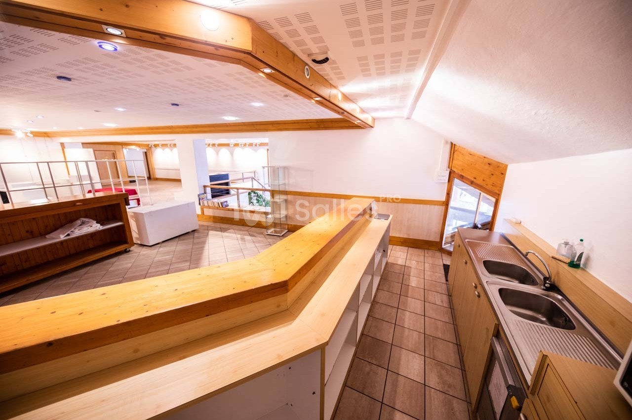 Cuisine ouverte avec un grand plan de travail en bois, double évier inox et vue sur un espace aménageable lumineux.