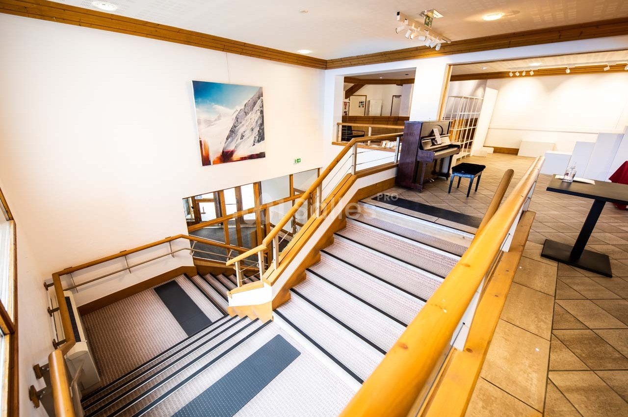 Escalier intérieur en bois et métal avec un piano à droite, dans un espace lumineux et moderne.