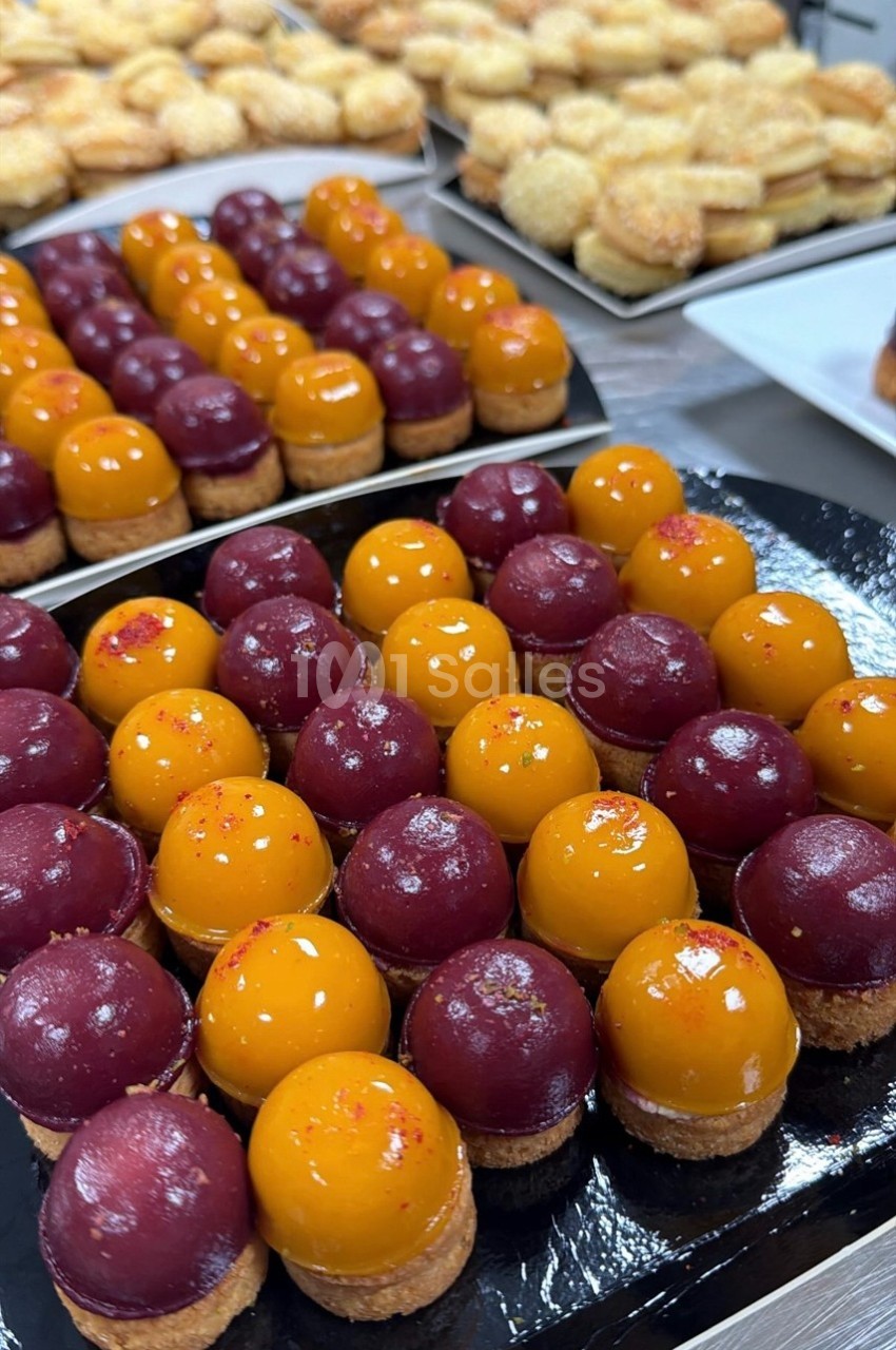 Plateau de petits desserts colorés avec glaçage jaune et rouge, disposés en rangées sur une table.