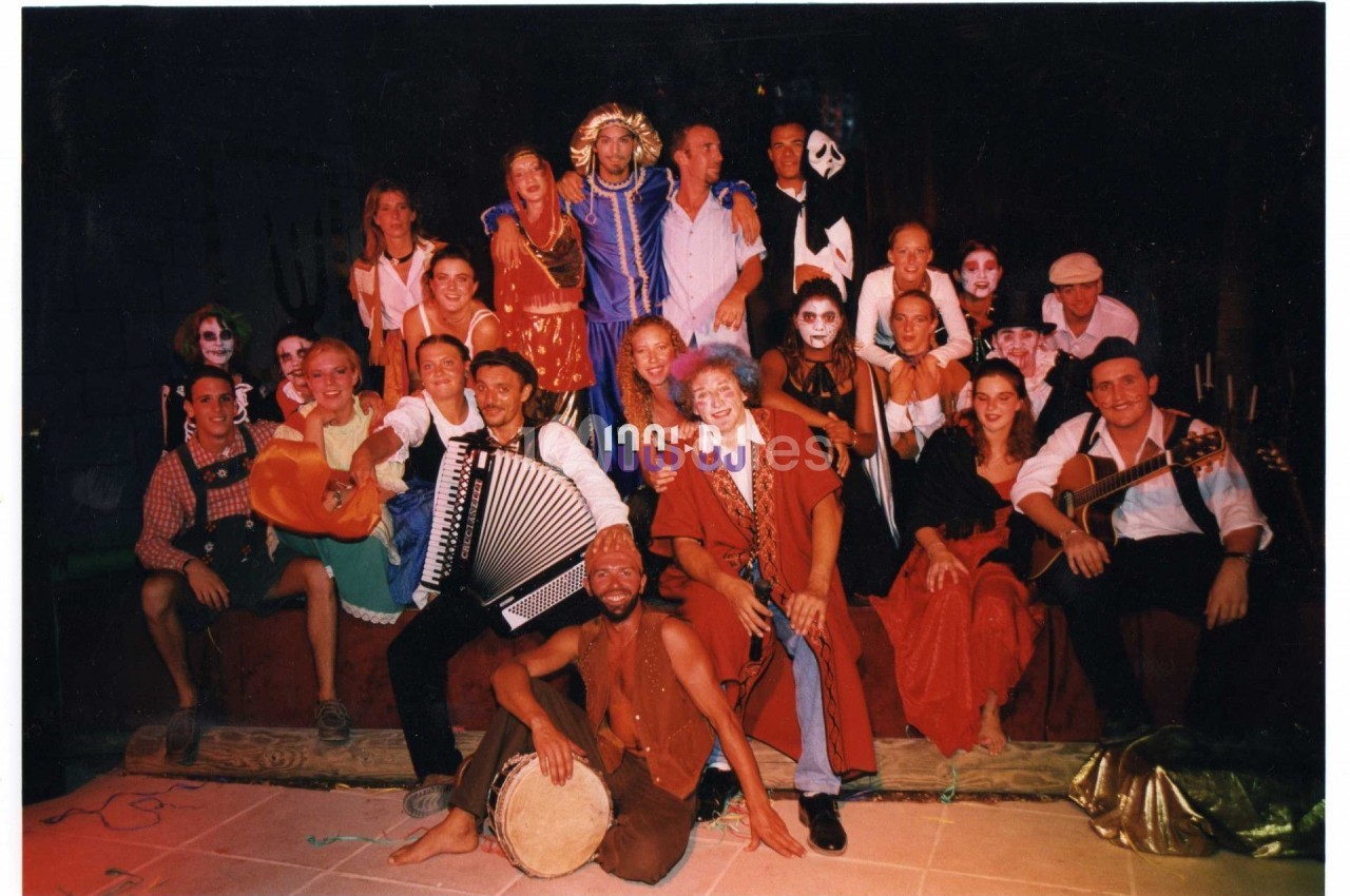 Un groupe de personnes en costumes colorés et maquillages variés posant sur une scène dans une ambiance festive.