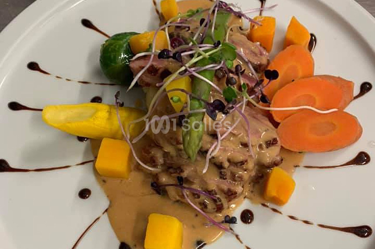 Assiette gastronomique composée de viande, légumes colorés, sauce crémeuse et décorations de réduction balsamique.