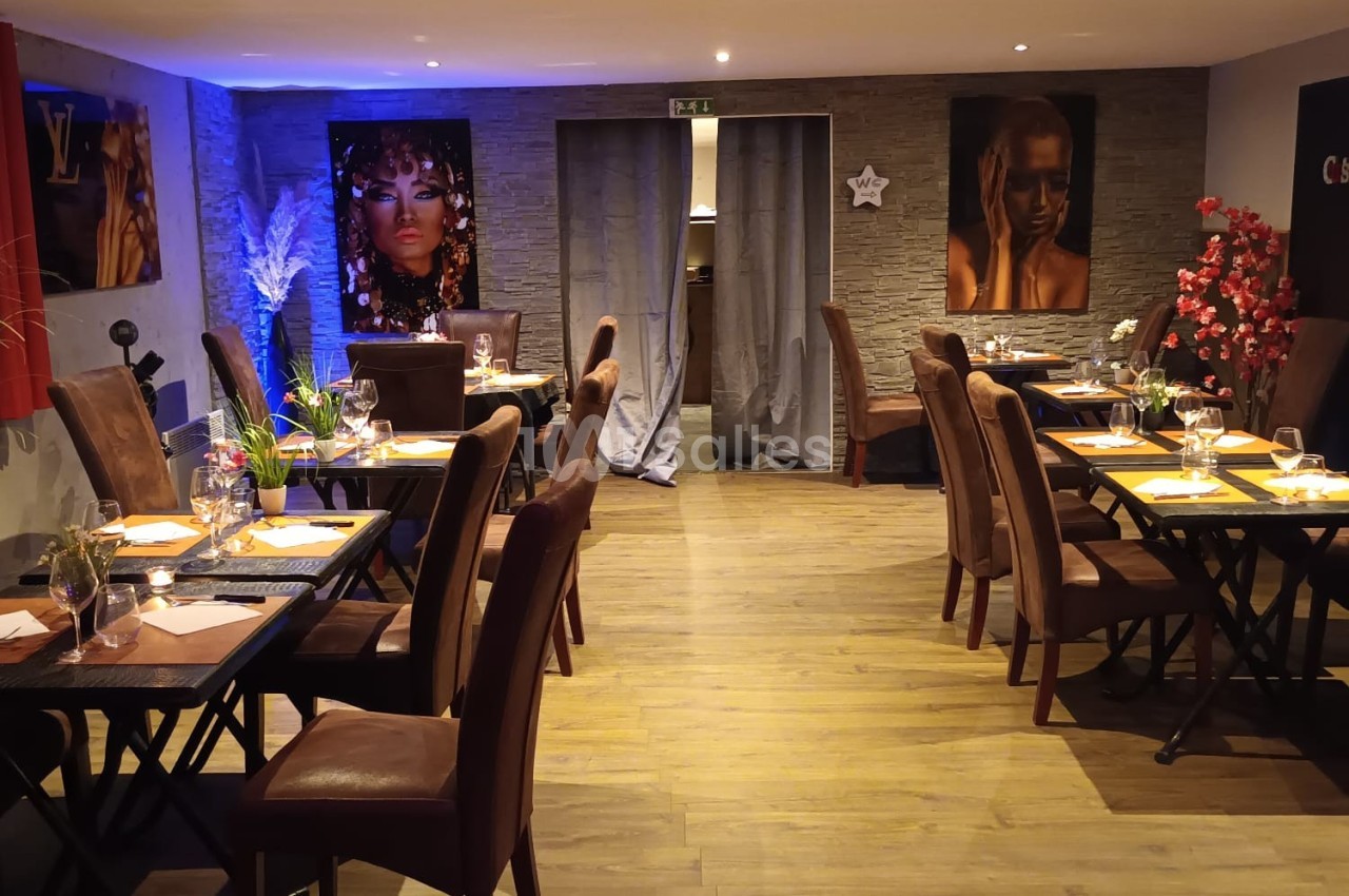 Salle de restaurant chaleureuse avec tables dressées, éclairage tamisé et décorations murales colorées.