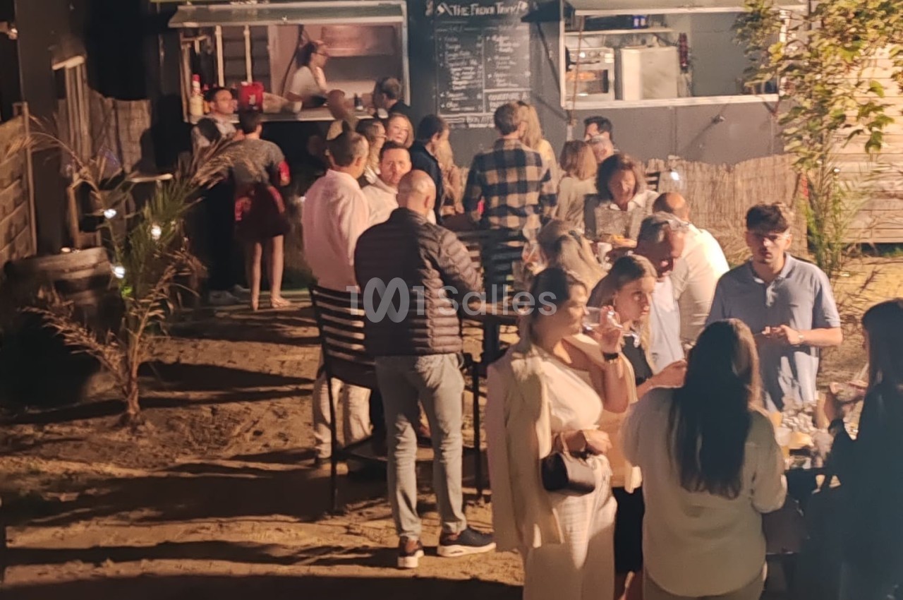Groupe de personnes rassemblées en soirée devant un food truck éclairé, dans un cadre extérieur convivial.