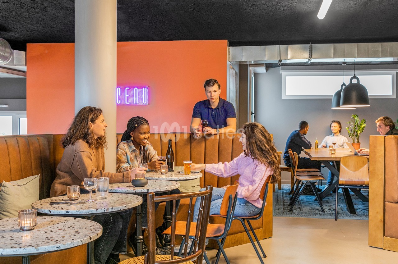 Des personnes discutent et partagent des boissons dans un café moderne avec une ambiance chaleureuse.