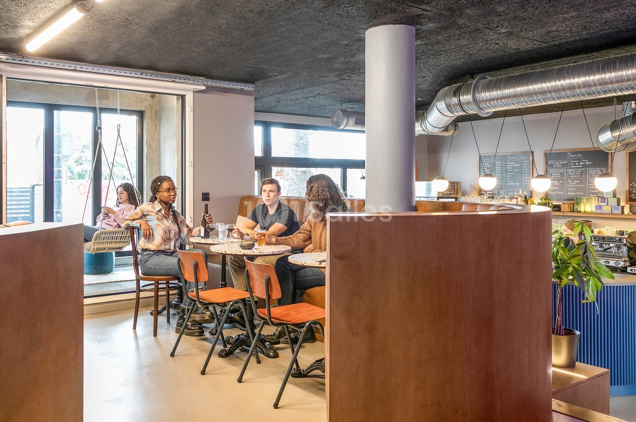 Des personnes discutent autour d'une table dans un café moderne avec un comptoir en arrière-plan.