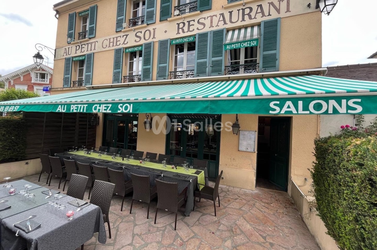 Façade d'un restaurant avec terrasse extérieure, tables dressées sous un auvent vert rayé.