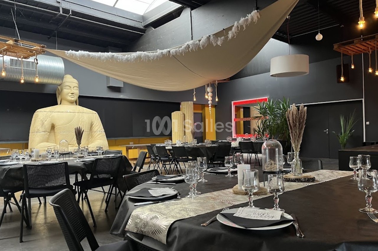 Salle de réception décorée avec des tables dressées, une grande statue et un tissu suspendu au plafond.