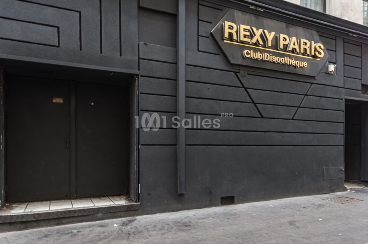 Façade noire d'une discothèque avec une enseigne dorée indiquant ’Rexy Paris’ et une porte d'entrée fermée.