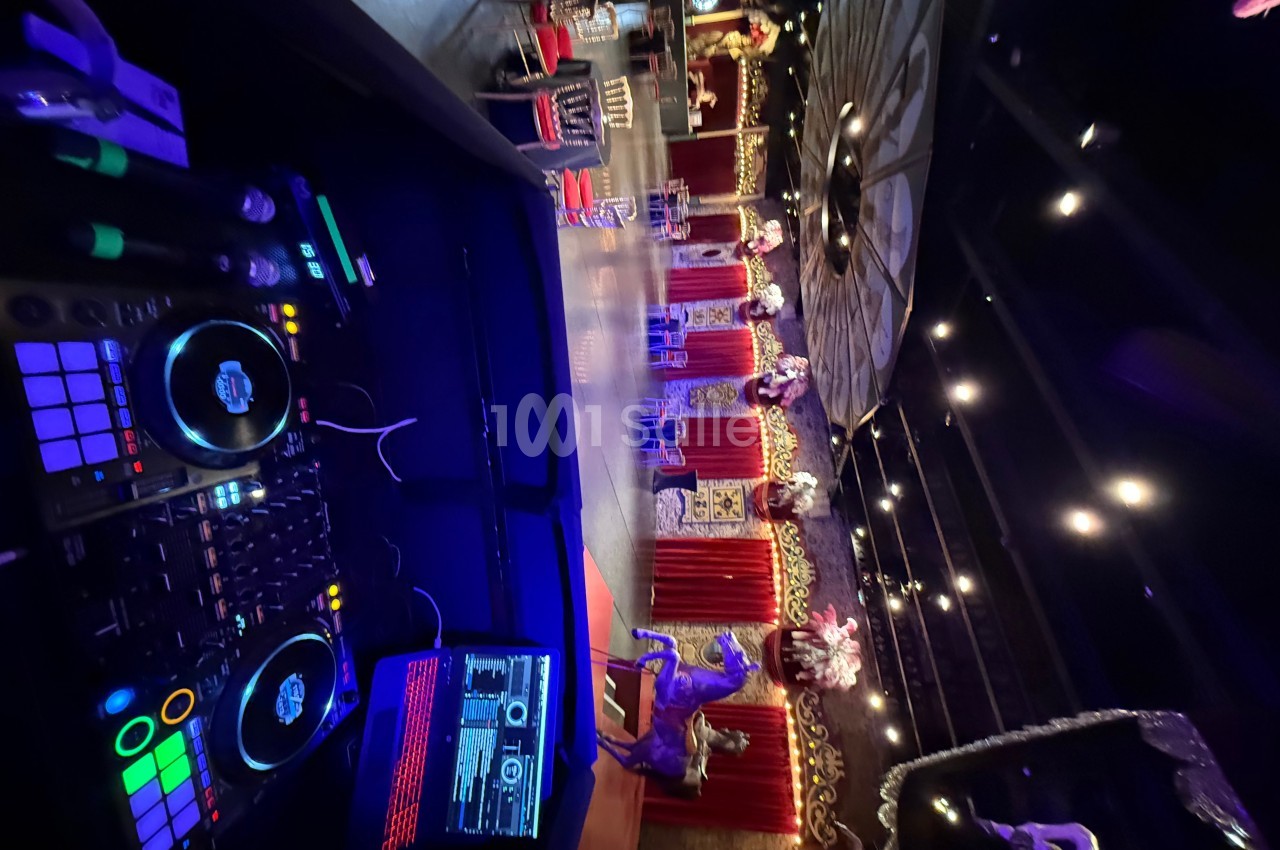 Vue d'une salle de spectacle décorée avec des lumières, des rideaux rouges et des éléments festifs, prise depuis une table…