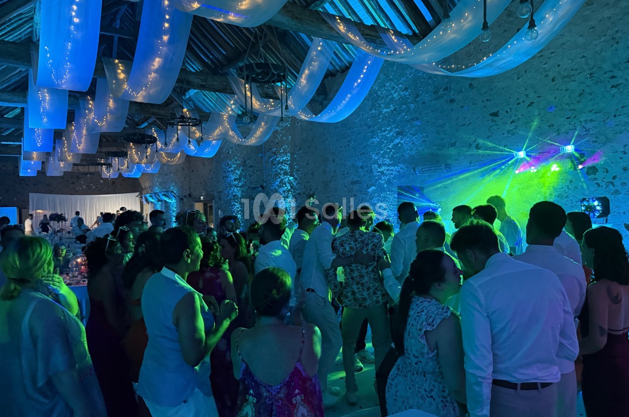 Groupe de personnes dans une salle en pierre éclairée par des lumières colorées lors d'une fête ou d'un événement.