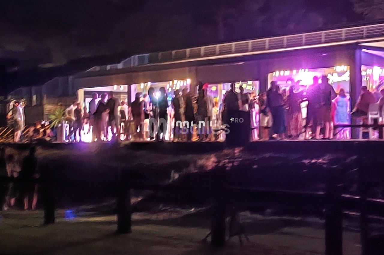 Groupe de personnes rassemblées devant un bâtiment illuminé, de nuit, avec une ambiance festive.