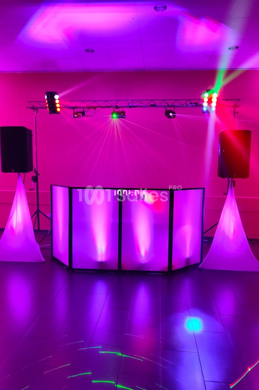 Équipement de sonorisation et éclairage lumineux rose installé dans une salle pour un événement festif.