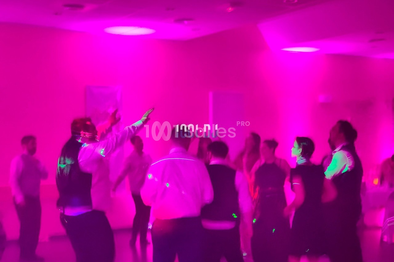 Des personnes dansent sous des lumières roses et violettes dans une salle sombre.