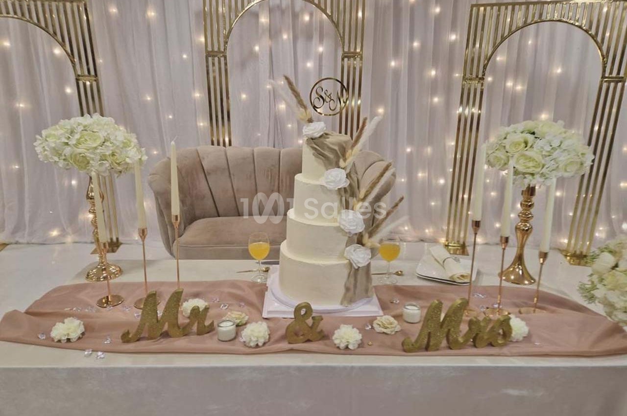 Gâteau de mariage à plusieurs étages décoré de fleurs séchées, entouré de bougies et d'arrangements floraux.
