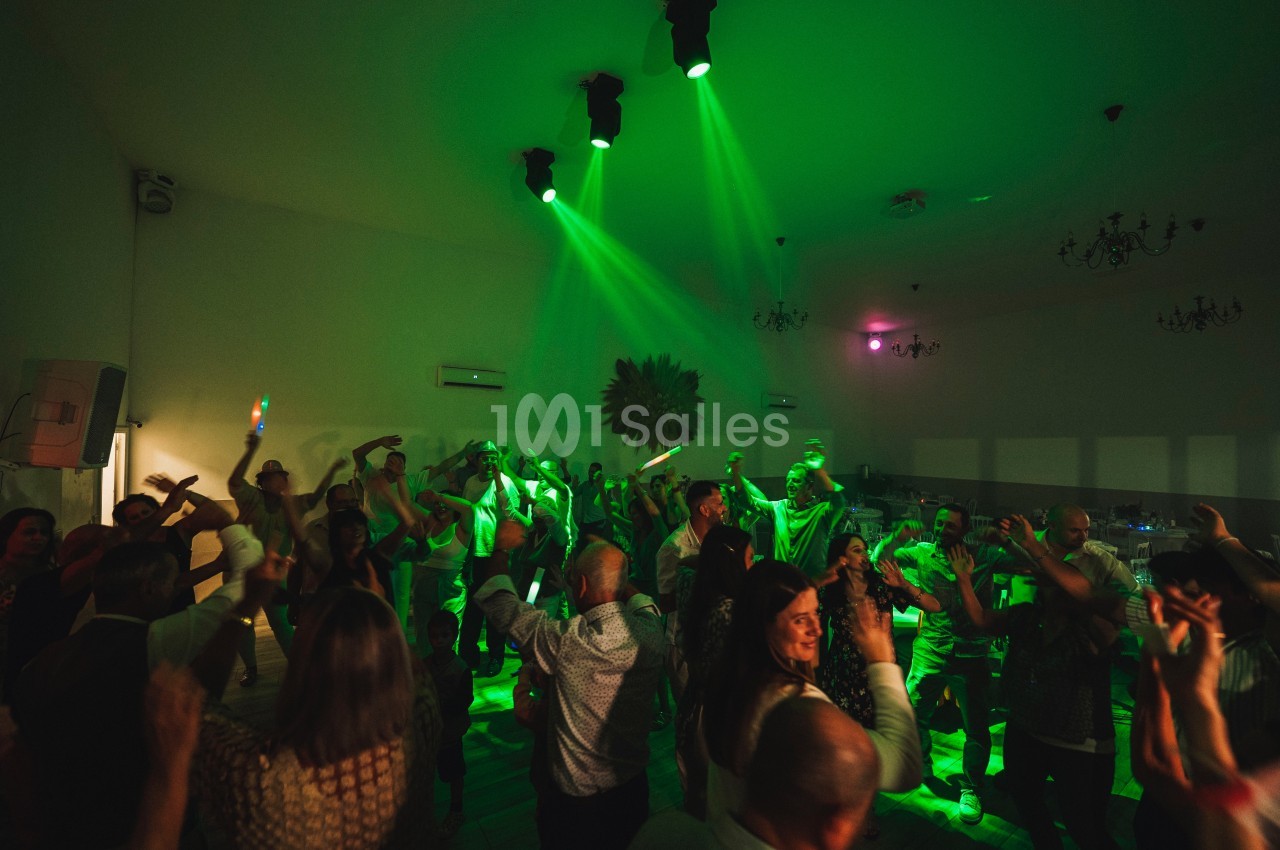 Groupe de personnes dansant sous des lumières vertes dans une salle sombre lors d'une fête ou d'un événement.