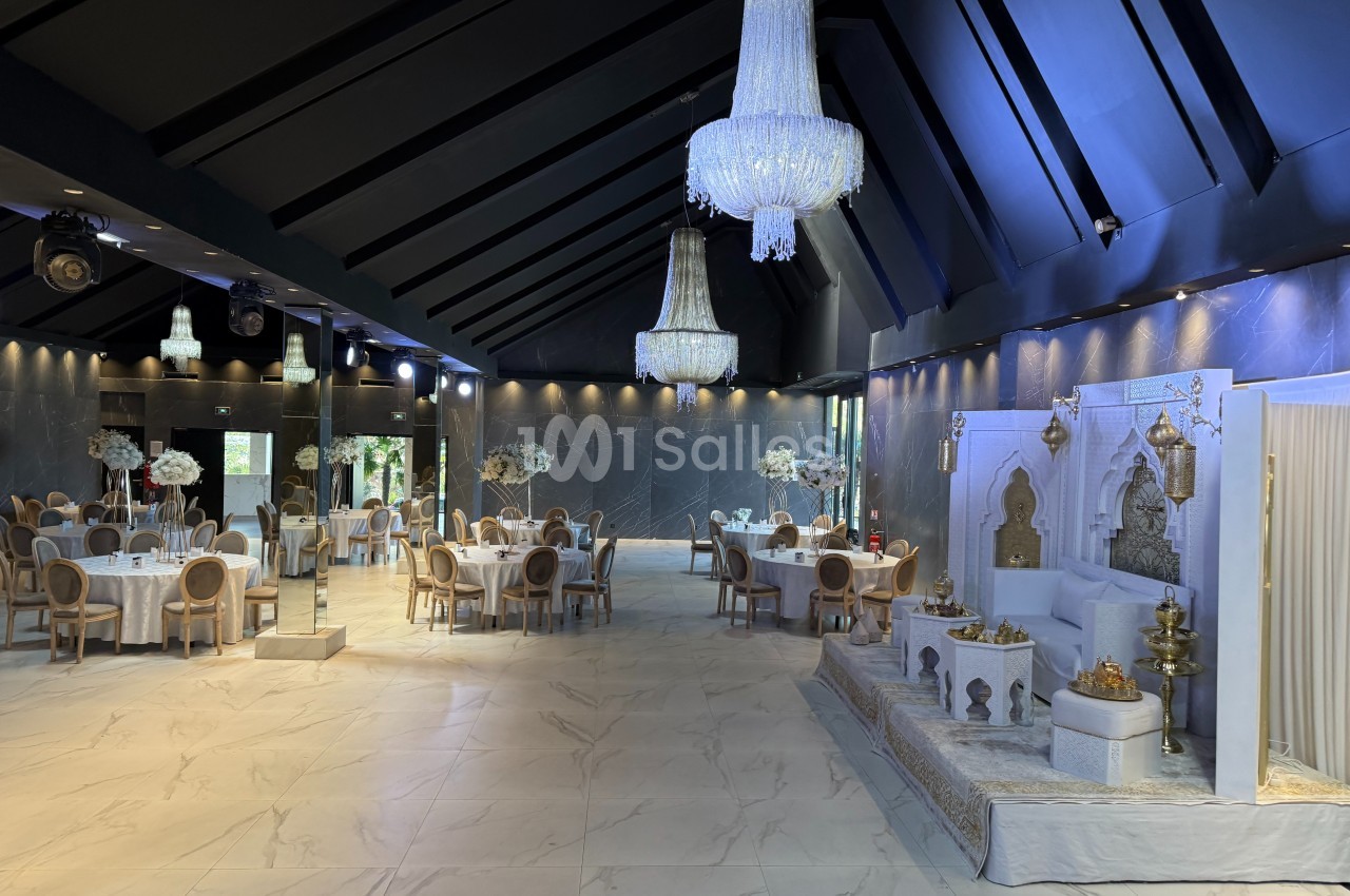 Salle de réception élégante avec tables décorées, lustres imposants et espace aménagé pour une cérémonie.