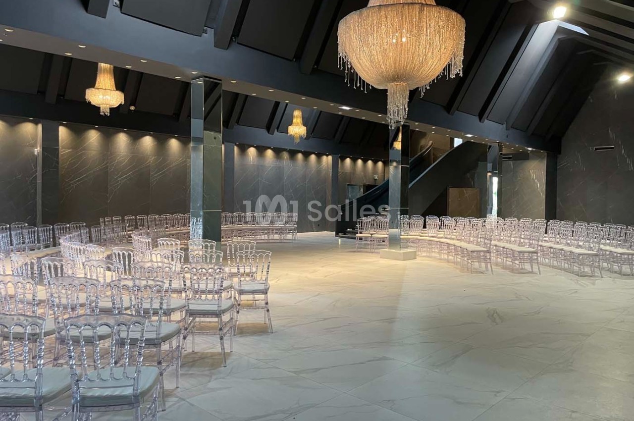 Salle de réception moderne avec chaises transparentes disposées en rangées et lustres en cristal suspendus.